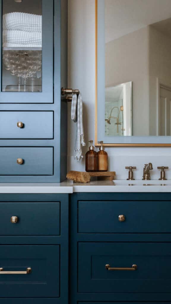 Custom inset maple bathroom vanity in Niwot CO by Harris Timberworks featuring brass hardware, glass upper cabinets, and furniture-style base design.
